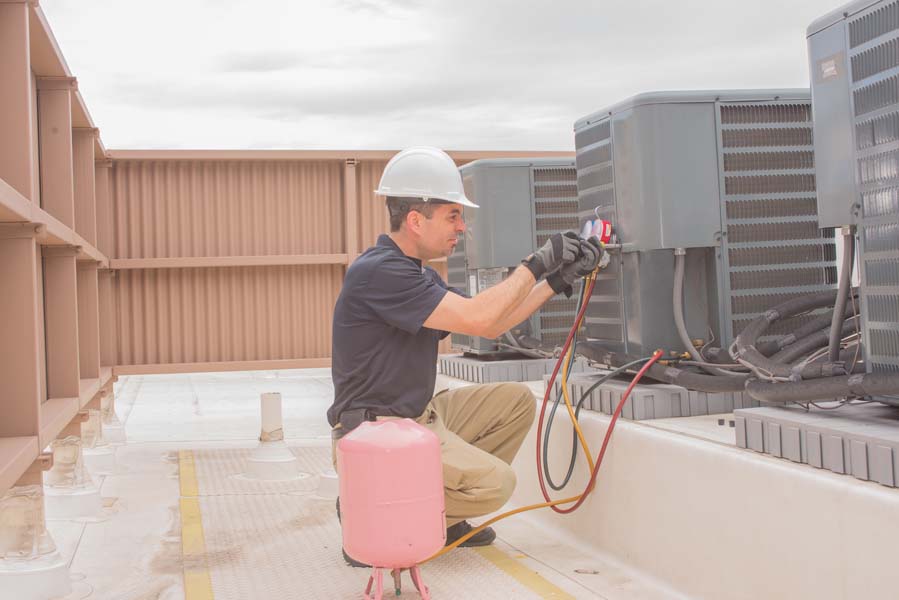 Technician taking a cover plate off an air conditioner condenser.