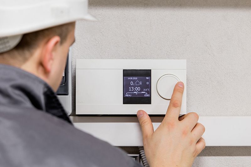 Image of a technician working on a thermostat. Why Schedule Air Conditioning Maintenance?