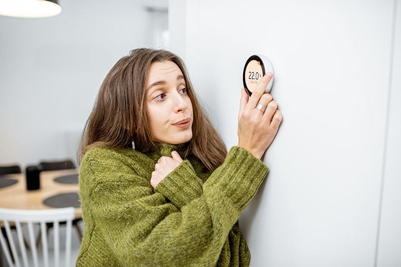 Why Is My Heat Pump Turning On and Off Frequently? - Woman Adjusting the Thermostat.